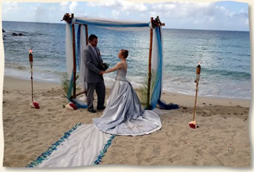 Bluebeards Beach wedding with blue arch, ailse, tiki torches and sea glass aisle.