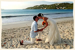Bride reaching for a kiss from groom on tropical beach wedding.