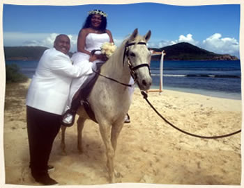 Bride on horse back with groom on beautiful beach in St. Thomas.
