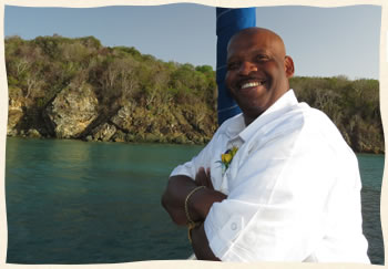 Groom waiting bow of sailboat for bride St James Virgin Islands cove.